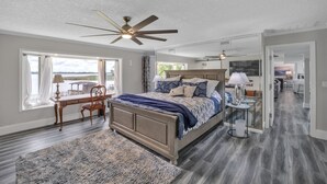 A bedroom with a large bed, a desk, and a chair. There is a ceiling fan and a window with curtains. - Beautiful Lake View Retreat Drivable To Theme Parks 3 Bedroom Home (Haines City)