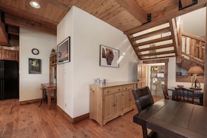 A rustic kitchen with wooden beams, a dining table, and a staircase. - 19th Hole 3 Bedroom Cabin (Granby)