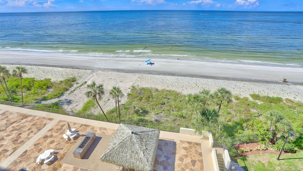 A beach view with a patio area featuring a thatched umbrella, outdoor seating, and a pool. - 🌞Beachfront🌊Ocean Sands I-808🌴Private Balcony🏖️Amazing Beach Views (Madeira Beach)