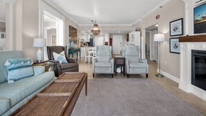 A spacious living room with a sofa, armchairs, and a coffee table. There is a fireplace and a dining area in the background. - 🏝️Stunning Beachfront Views-Pool-Navarre Towers 504🏝️ (Navarre Beach)