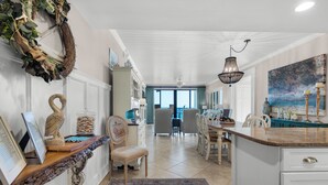 A spacious kitchen with a central island, white cabinetry, and a view to the dining area. - 🏝️Stunning Beachfront Views-Pool-Navarre Towers 504🏝️ (Navarre Beach)