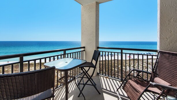 A balcony with a table and chairs, overlooking a beach and ocean. - 🏝️Stunning Beachfront Views-Pool-Navarre Towers 504🏝️ (Navarre Beach)