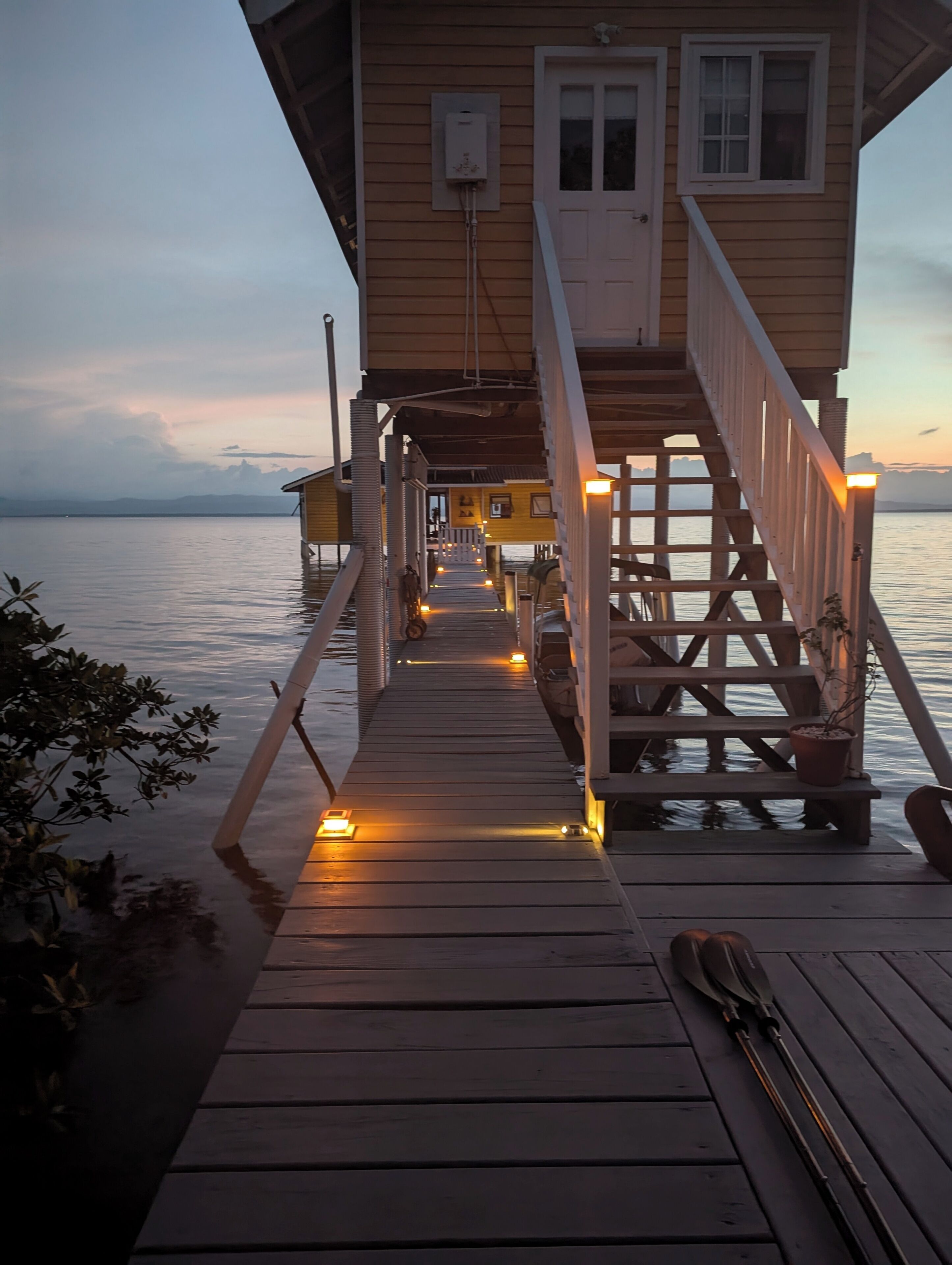 A wooden pier leading to a cabin with a door and windows, overlooking a calm body of water.