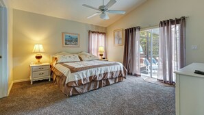 A bedroom with a bed, two bedside tables with lamps, a ceiling fan, and a view through a glass door to an outdoor area. - Spacious 4-bed lakeside pool villa near Disney (Kissimmee)