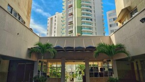 A high-rise building with multiple balconies, a clear blue sky, and a central courtyard with palm trees. - PARCEROS GROUP - 2 BEDROOM VACATION APARTMENT, 10TH FLOOR, CARTAGENA, SPAIN (Cartagena de Indias)