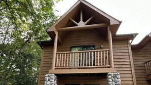 A two-story lodge with a balcony, stone pillars, and a front door. - Cozy 2-bedroom cabin steps away from starved rock state park (North Utica)