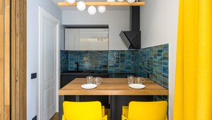 A compact kitchen with a wooden table, two yellow chairs, and a modern pendant light fixture. - Tribunali Trendy Studio by Wonderful Italy (Napoli)