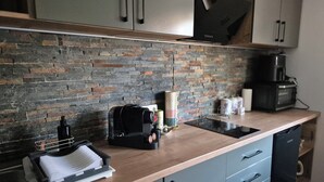 A modern kitchen with a stone backsplash, a coffee machine, a microwave, and a dishwasher. - OTILIA apartment (Zell am See)