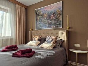 A bedroom with a large bed, two pillows with deer designs, a painting of a cabin, a bedside table, and a window with curtains. - OTILIA apartment (Zell am See)