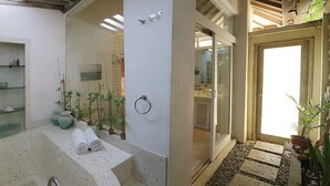 Un baño moderno con una bañera independiente, una ducha con mampara de vidrio y varias plantas.