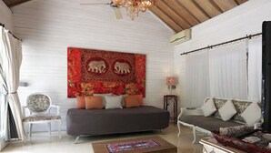 Una sala de estar con sofá, sillón, mesa de centro y un tapiz en la pared.