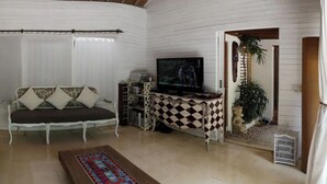 Una sala de estar con un sofá, un televisor, una mesa con estampado y un tapete decorativo.