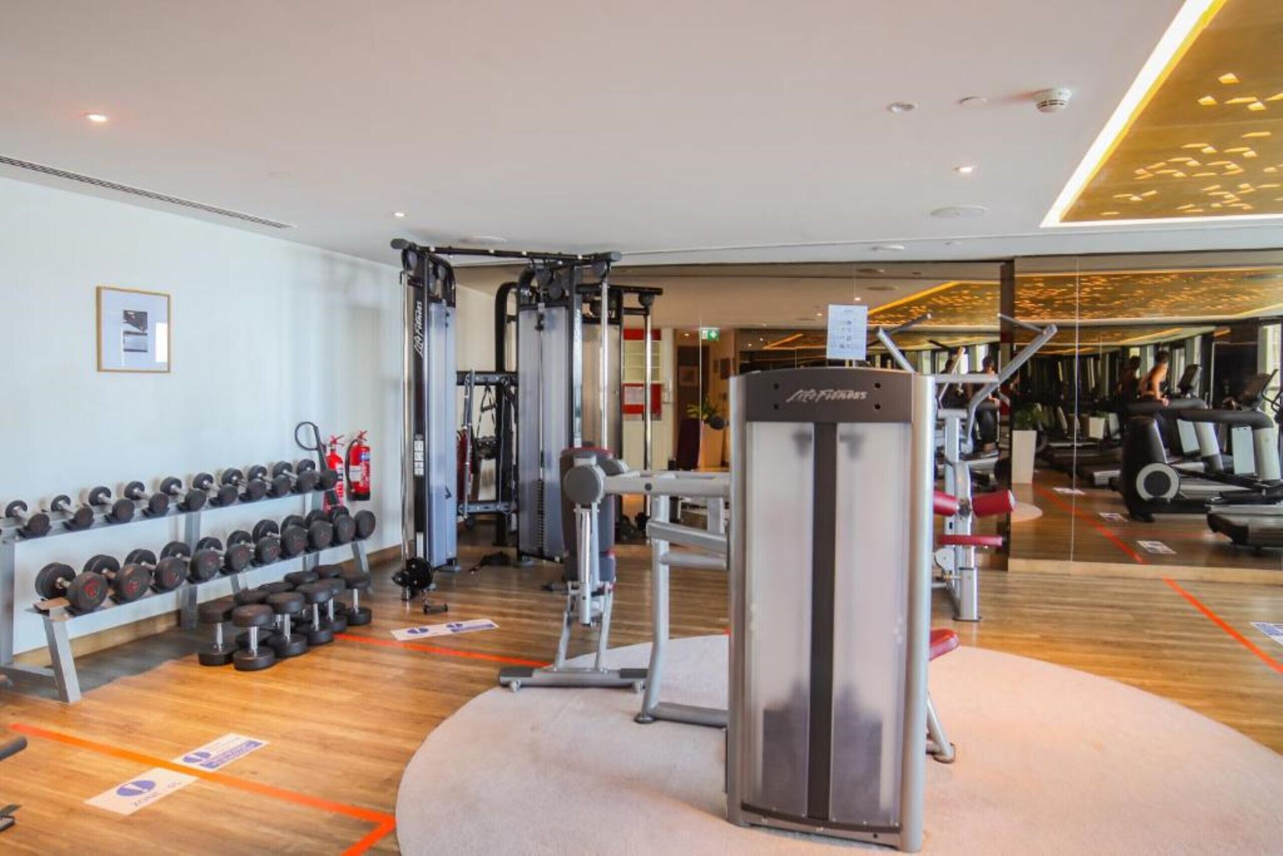 A gym with various exercise equipment, including dumbbells, a cable machine, and a weight stack.