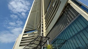 Un immeuble moderne de grande hauteur, doté d’une façade incurvée, de grandes fenêtres et surplombant un ciel dégagé.