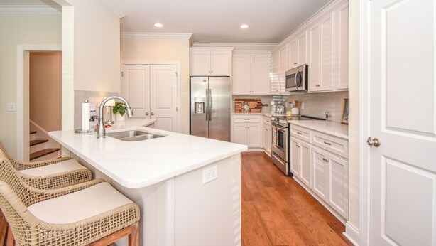 A modern kitchen with white cabinetry, stainless steel appliances, and a central island with seating. - Southern Charmer in Auburn, condo sleeps 8! Comes w/gameday parking pass! (Auburn)
