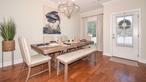 A dining room with a wooden table, upholstered chairs, a bench, a chandelier, and a large painting on the wall. - Southern Charmer in Auburn, condo sleeps 8! Comes w/gameday parking pass! (Auburn)