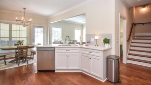 Una cocina moderna con armarios blancos, una isla central y un bote de basura de acero inoxidable.