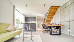 En moderne stue med sofa, spisebord og trappe.