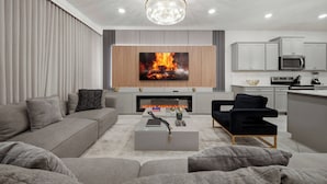 Una sala de estar moderna con chimenea, televisor de pantalla plana y zona de cocina.