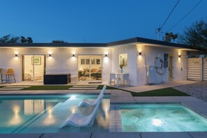 Ein modernes Haus mit Schwimmbad, Rutsche und einer Terrassenfläche.