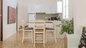 Una cocina amplia con armarios blancos, encimera de granito y comedor con mesa y sillas.