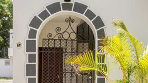 Un edificio blanco con una verja metálica negra y una entrada en arco.