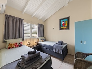 A bedroom with two beds, a wardrobe, and a painting on the wall.