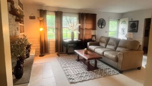 Un salon avec un canapé beige, une table basse en bois, un tapis à motifs et une cheminée en pierre.