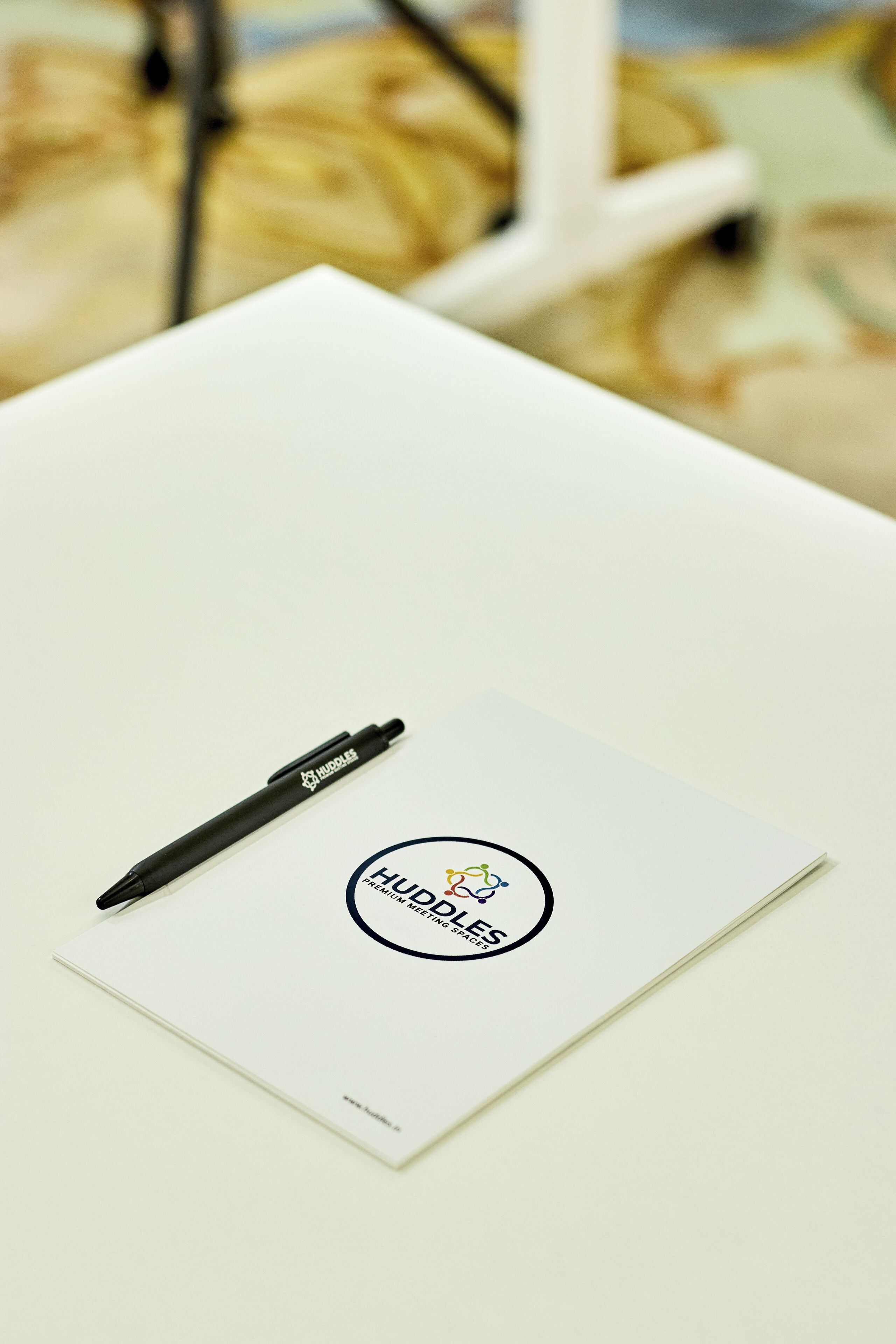 Une table blanche sur laquelle se trouvent un stylo noir et une carte de visite.