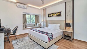 Una habitación de hotel moderna con una cama grande, un escritorio con silla, un asiento junto a la ventana y un ventilador de techo.
