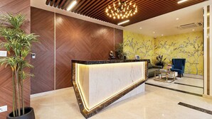Una moderna zona de recepción con mostrador de mármol, paneles de madera y un papel tapiz floral amarillo.
