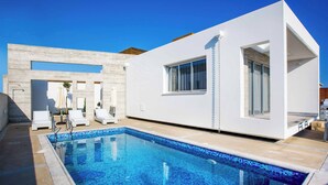 A modern poolside area with a clear blue pool, white walls, and a minimalist design. - Villa Cerulean Paphos (Pafos)