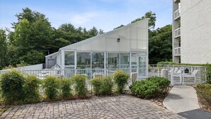 A modern building with a glass facade, surrounded by a paved courtyard and greenery. - Spacious 3-BR Condo for 8 w Resort Pools, Hot Tub, and Free Dollywood Ticket (Pigeon Forge)