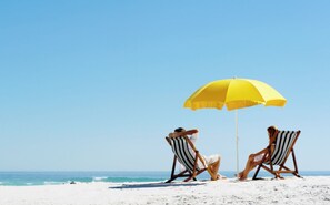Two beach chairs under a yellow umbrella on a sandy beach with the ocean in the background. - Sportsplex.PetFriendly.OWA.GasGrill.Foosball.FullyFencedYard (Foley)