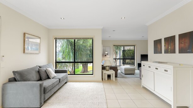 A modern living room with a grey sofa, a small table, and a TV. There are large windows with a view of greenery outside. - El Penguini in Cowes (Cowes)