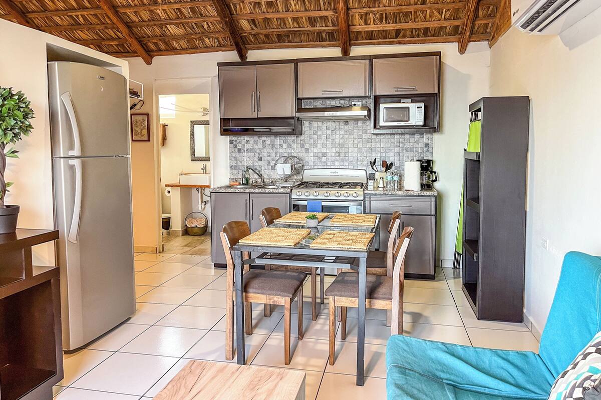 Una cocina compacta con una isla central, un refrigerador y un microondas.
