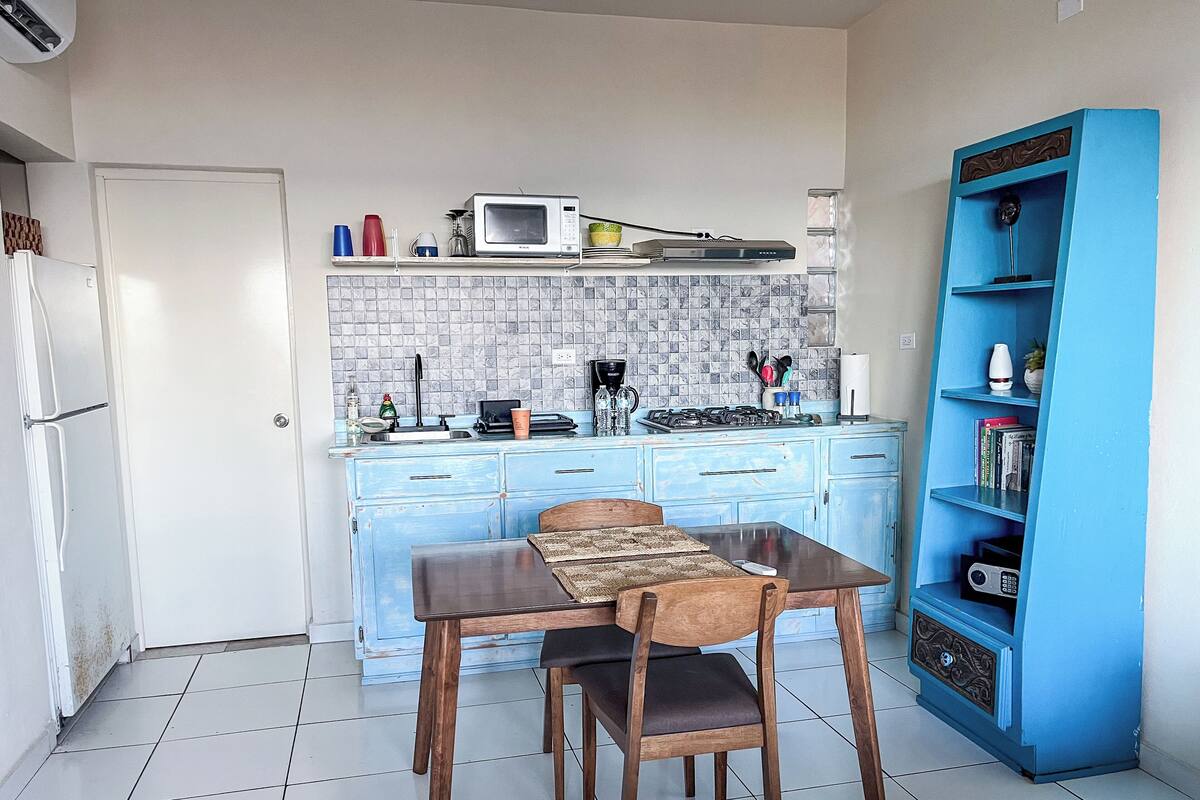 Una cocina con armarios azules, un microondas, una estufa a gas y una librería azul.