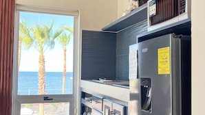 Une cuisine moderne avec vue sur la mer, un réfrigérateur en acier inoxydable et une fenêtre avec des rideaux.