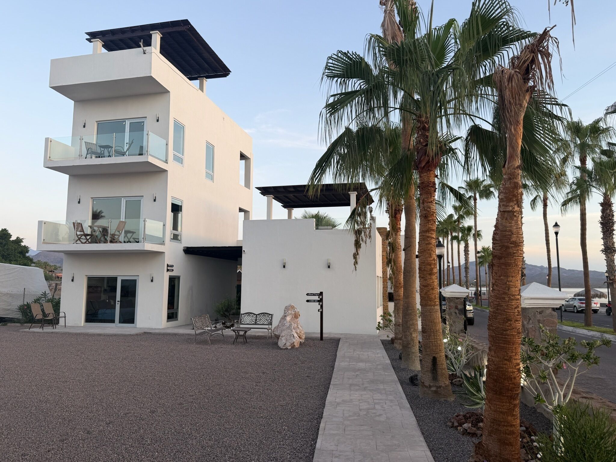 A modern two-story building with a flat roof, a covered patio, and a gravel driveway.