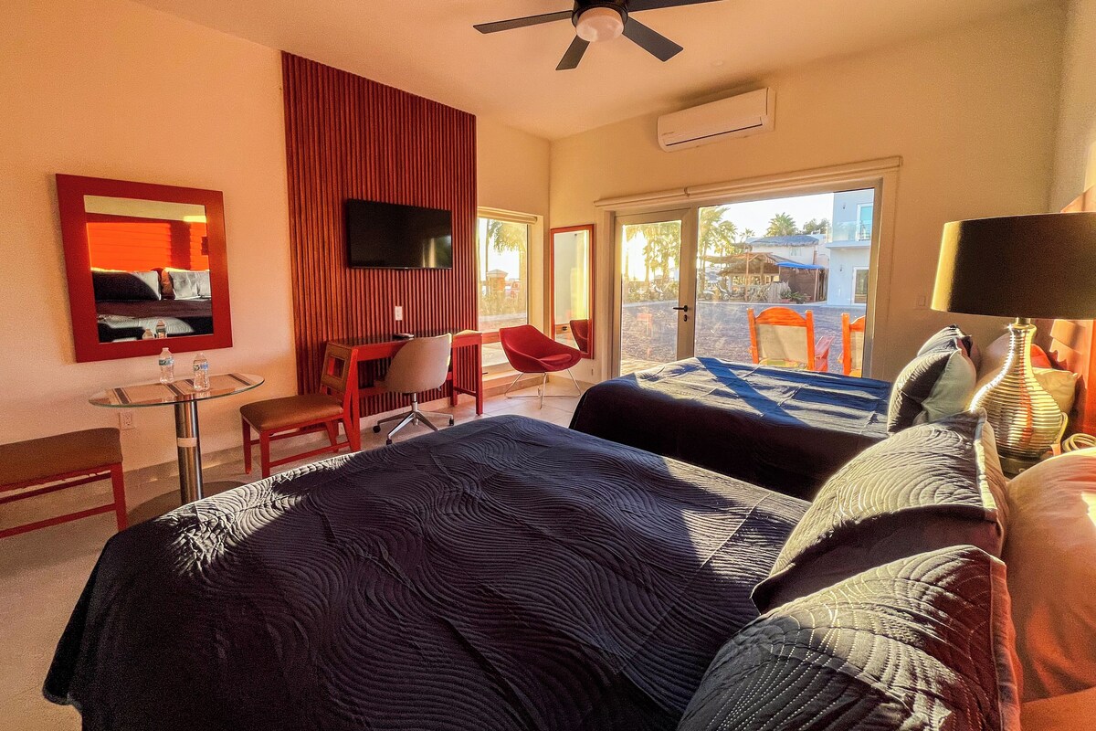 A hotel room with a bed, a desk, a chair, a TV, and a window with a view of the outside.