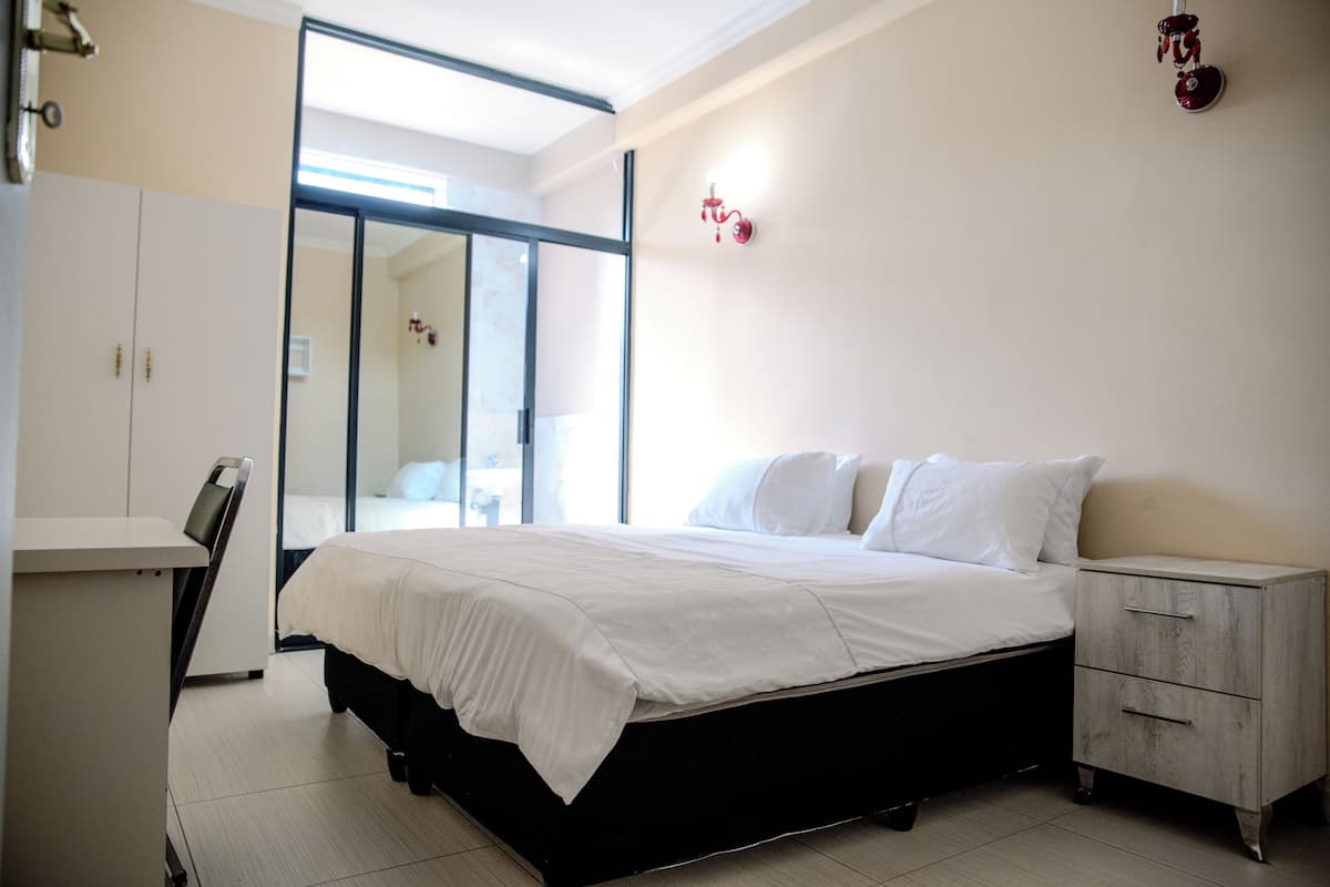 A bedroom with a bed, a desk, and a wardrobe.
