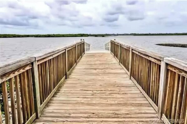 Un muelle de madera que se adentra en una masa de agua bajo un cielo nublado.