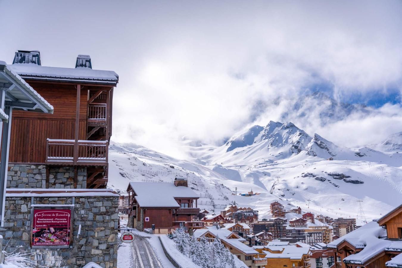 A snow-covered mountain town with wooden buildings and a sign for a restaurant.