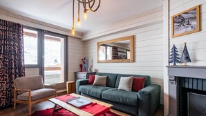 A cozy living room with a green sofa, wooden coffee table, and a fireplace. - 1st floor, swimming pool, sauna, hammam, balcony, fireplace or stove, tv, ski locker, 68m² (Val Thorens)