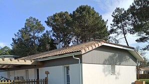 Ein eingeschossiges Haus mit Ziegeldach, einer kleinen Veranda und einem Rasen.