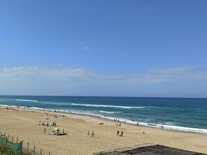 Una playa con gente, sombrillas y una valla.