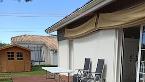 Eine Holzterrasse mit Tisch und Stühlen, eine überdachte Veranda und ein Haus mit einer Schiebetür.