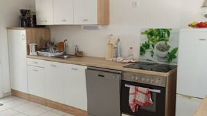 Eine moderne Küche mit weißen Schränken, einem Geschirrspüler, einem Backofen und einer Kaffeemaschine.