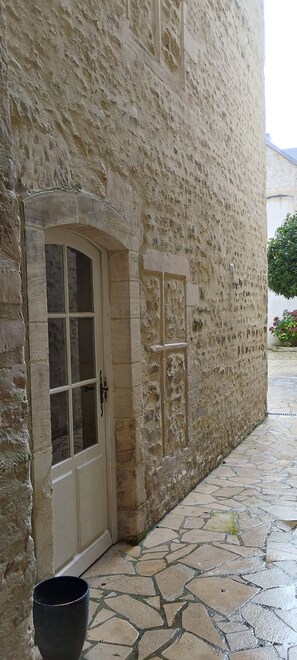 A stone building with a large arched doorway and a small window.