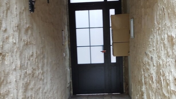 A narrow stone-paved corridor with a wooden ceiling and a black door at the end. - Bayeux, Appartement Le Clem's'right in the heart of town and tourist sites. (Bayeux)